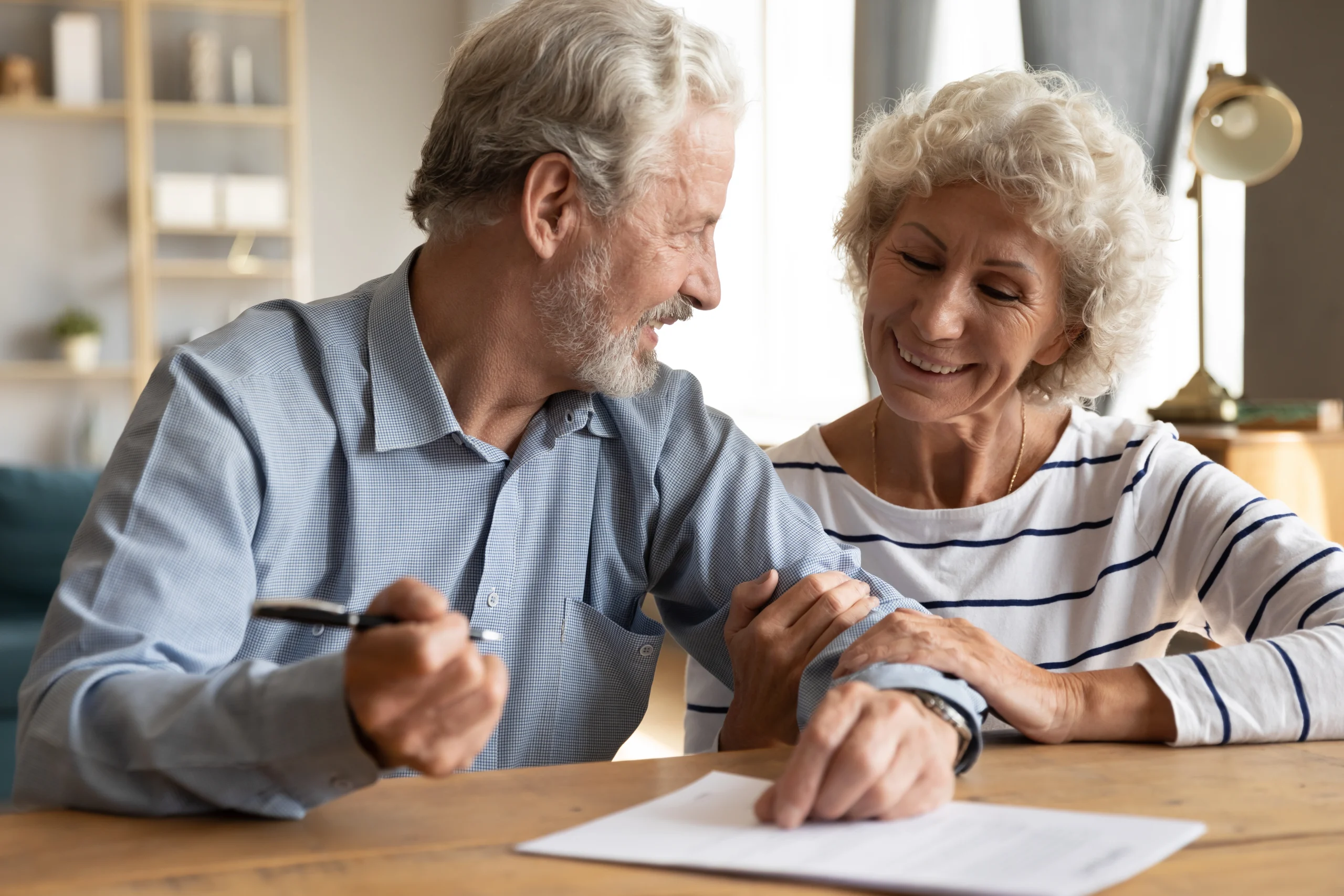 happy-old-mature-retired-family-couple-putting-signature-paper-document-feeling-satisfied-with-purchasing-own-apartment-house-signing-medical-insurance-agreement-together-office-meeting